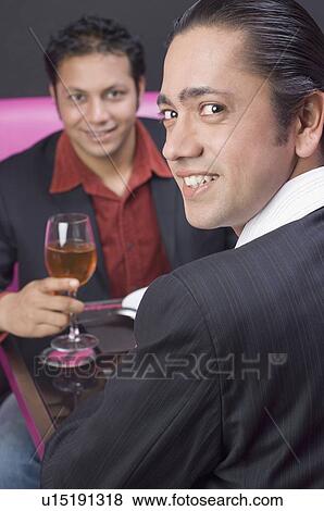 Stock Photo - Portrait of a mid adult man sitting with a young man in a restaurant and smiling. Fotosearch