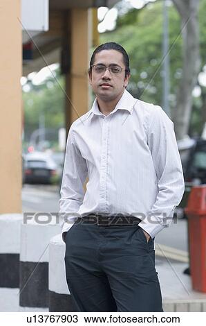 Stock Image - Portrait of a mid adult man standing with his hands in his pockets. Fotosearch