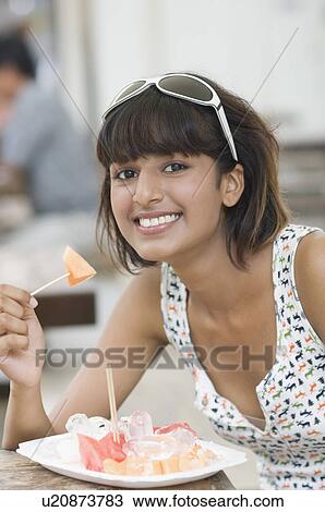 Stock Image - Portrait of a mid adult woman eating fruit salad. Fotosearch