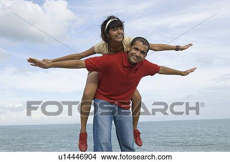 Portrait of a mid adult woman riding piggyback on a young man View Large Photo Image Picture - Portrait of a mid adult woman riding piggyback on a young man. Fotosearch