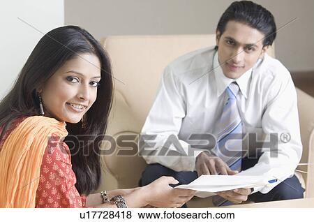 Stock Photo - Portrait of a real estate agent discussing a document with a young woman. Fotosearch