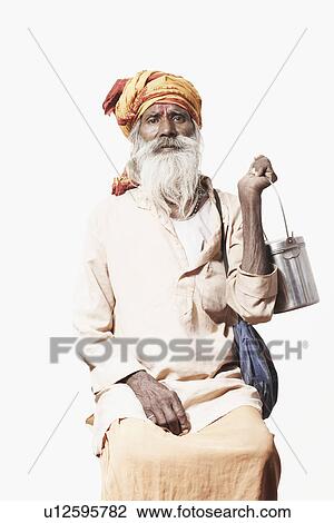 Stock Image - Portrait of a sadhu sitting and holding a utensil. Fotosearch