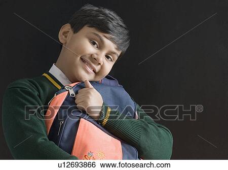 Stock Photograph - Portrait of a schoolboy holding his schoolbag. Fotosearch