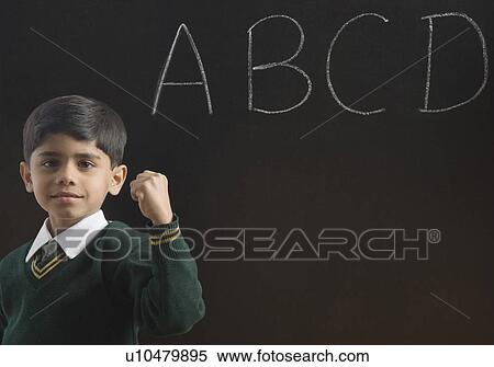 Stock Photography - Portrait of a schoolboy showing his fist in a classroom. Fotosearch