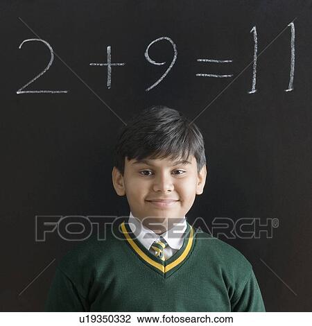 Stock Image - Portrait of a schoolboy smiling in front of a blackboard. Fotosearch