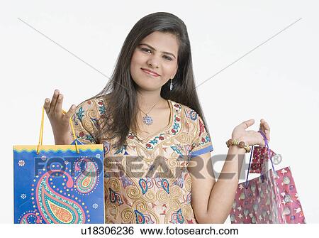 Stock Photograph - Portrait of a teenage girl holding shopping bags and smirking. Fotosearch