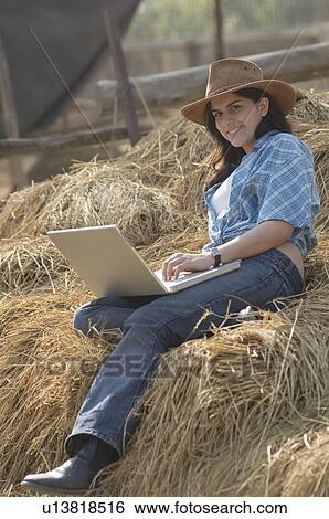 Portrait of a teenage girl sitting on a haystack and using a laptop View Large Photo Image Stock Photograph - Portrait of a teenage girl sitting on a haystack and using a laptop. Fotosearch