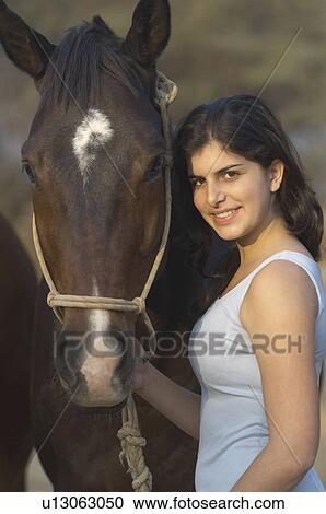 Portrait of a teenage girl standing with a horse and smiling View Large Photo Image Stock Image - Portrait of a teenage girl standing with a horse and smiling. Fotosearch