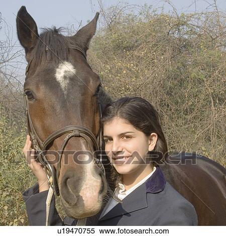 Stock Photography - Portrait of a teenage girl standing with a horse and smiling. Fotosearch