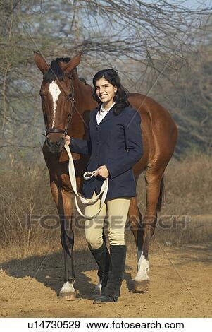 Stock Photo - Portrait of a teenage girl walking with a horse and smiling. Fotosearch