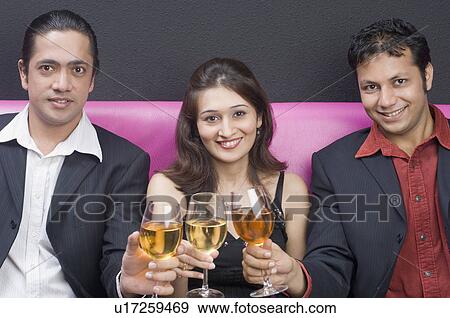 Stock Photo - Portrait of a young couple and a mid adult man toasting with wine glasses. Fotosearch
