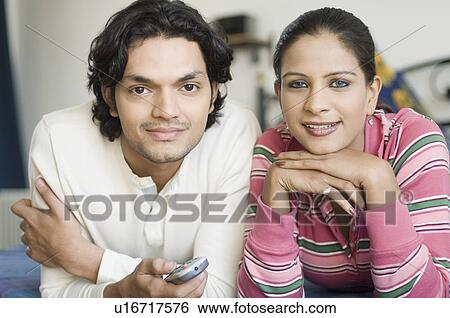 Portrait of a young couple lying on a bed and watching television View Large Photo Image Stock Photograph - Portrait of a young couple lying on a bed and watching television. Fotosearch