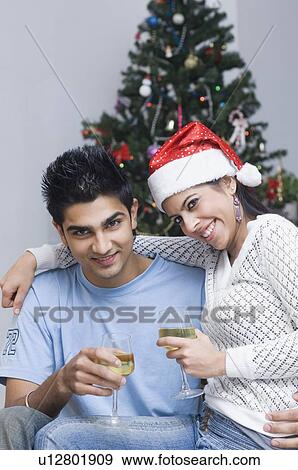 Stock Photo - Portrait of a young couple smiling and holding wine glasses. Fotosearch