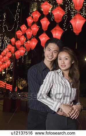 Stock Photograph - Portrait of a young man embracing a young woman from behind. Fotosearch