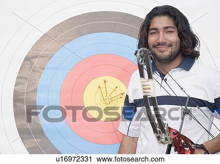 Stock Image - Portrait of a young man holding a bow and smirking. Fotosearch