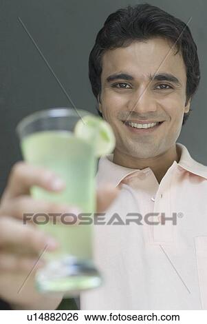 Stock Photograph - Portrait of a young man holding a glass of lemonade and smiling. Fotosearch