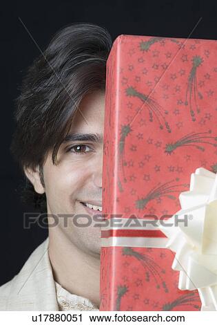 Portrait of a young man holding a present View Large Photo Image Stock Image - Portrait of a young man holding a present. Fotosearch