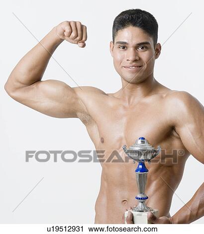 Portrait of a young man holding a trophy and flexing his biceps View Large Photo Image Stock Image - Portrait of a young man holding a trophy and flexing his biceps. Fotosearch