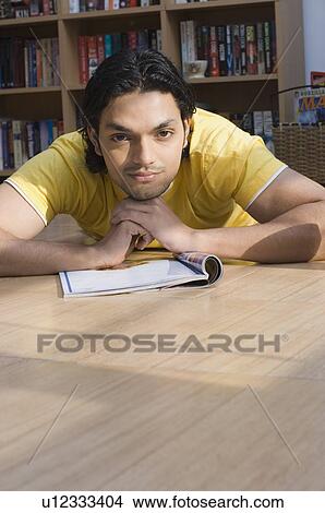 Portrait of a young man lying on the floor of a library and thinking View Large Photo Image Picture - Portrait of a young man lying on the floor of a library and thinking. Fotosearch