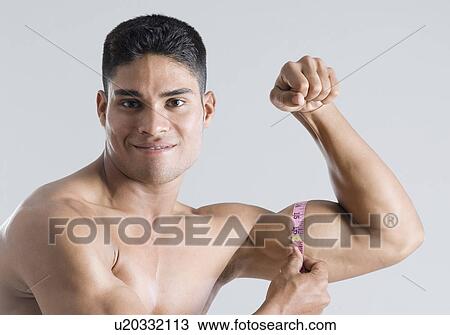 Portrait of a young man measuring his biceps with a tape measure View Large Photo Image Stock Image - Portrait of a young man measuring his biceps with a tape measure. Fotosearch
