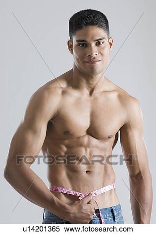 Portrait of a young man measuring his waist with a tape measure View Large Photo Image Stock Photography - Portrait of a young man measuring his waist with a tape measure. Fotosearch