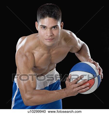 Stock Image - Portrait of a young man playing a basketball. Fotosearch