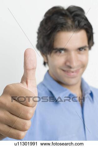 Portrait of a young man showing thumbs up sign View Large Photo Image Stock Image - Portrait of a young man showing thumbs up sign. Fotosearch