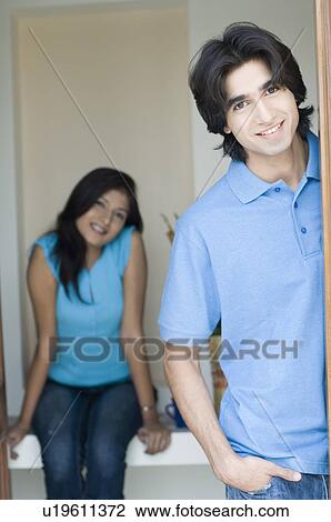 Portrait of a young man smiling with a young woman sitting behind him View Large Photo Image Stock Image - Portrait of a young man smiling with a young woman sitting behind him. Fotosearch