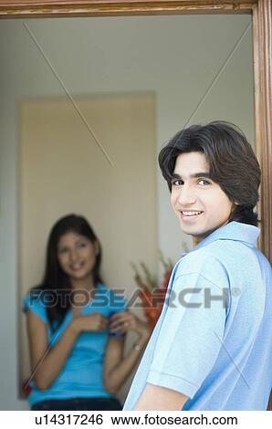 Portrait of a young man smiling with a young woman sitting in the background View Large Photo Image Stock Photograph - Portrait of a young man smiling with a young woman sitting in the background. Fotosearch