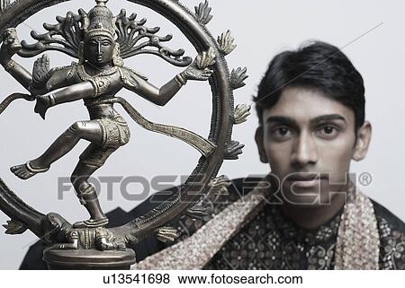 Stock Photo - Portrait of a young man with the Nataraja Statue. Fotosearch