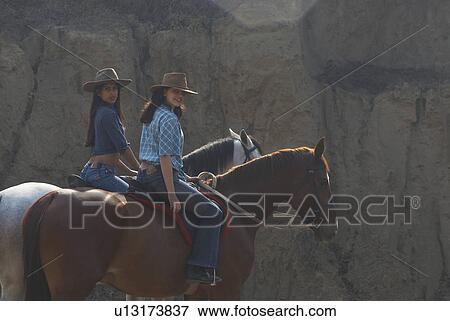 Stock Photo - Portrait of a young woman and a teenage girl riding horses. Fotosearch