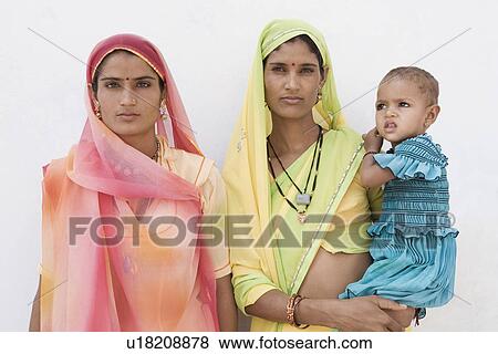 Portrait of a young woman carrying her daughter with another young woman standing beside them View Large Photo Image Stock Photo - Portrait of a young woman carrying her daughter with another young woman standing beside them. Fotosearch