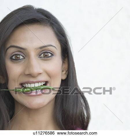 Portrait of a young woman eating a green chili View Large Photo Image Stock Photograph - Portrait of a young woman eating a green chili . Fotosearch