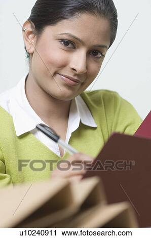 Portrait of a young woman holding a pen View Large Photo Image Stock Image - Portrait of a young woman holding a pen. Fotosearch