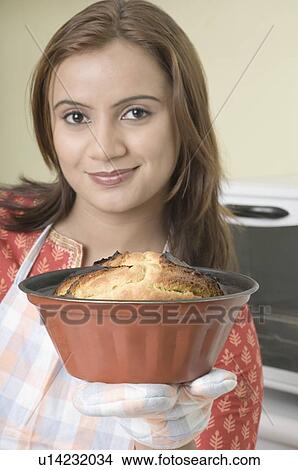 Portrait of a young woman holding a cake in a mould View Large Photo Image Picture - Portrait of a young woman holding a cake in a mould. Fotosearch