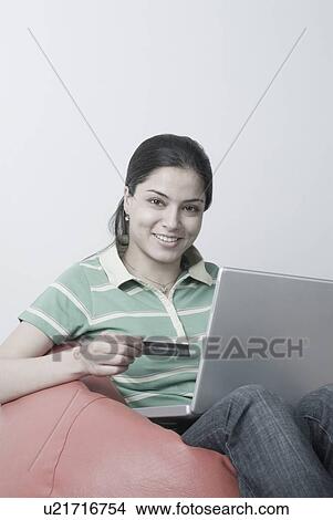 Portrait of a young woman holding a credit card and using a laptop View Large Photo Image Picture - Portrait of a young woman holding a credit card and using a laptop. Fotosearch