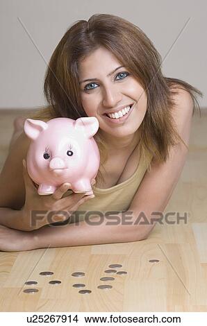 Portrait of a young woman holding a piggy bank View Large Photo Image Picture - Portrait of a young woman holding a piggy bank. Fotosearch