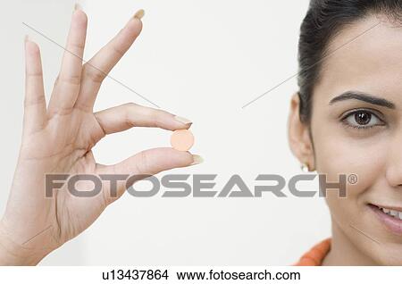 Portrait of a young woman holding a pill View Large Photo Image Picture - Portrait of a young woman holding a pill. Fotosearch