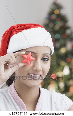 Stock Image - Portrait of a young woman holding a star shaped candle in front of her eyes. Fotosearch