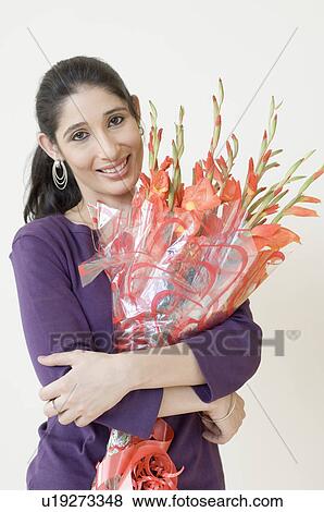 Stock Photo - Portrait of a young woman holding a bouquet of flowers and smiling. Fotosearch