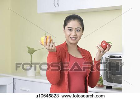 Portrait of a young woman holding bell peppers and smiling View Large Photo Image Stock Image - Portrait of a young woman holding bell peppers and smiling. Fotosearch