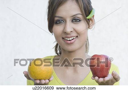 Portrait of a young woman holding fruits View Large Photo Image Stock Photo - Portrait of a young woman holding fruits. Fotosearch