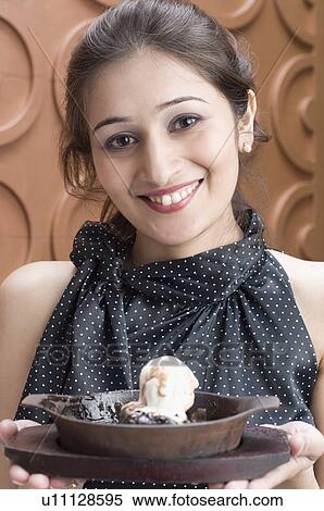 Stock Photography - Portrait of a young woman holding ice cream on a tray. Fotosearch