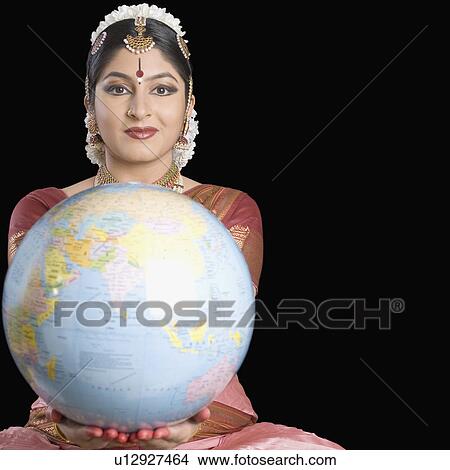 Picture - Portrait of a young woman performing Bharatnatyam and holding a globe. Fotosearch