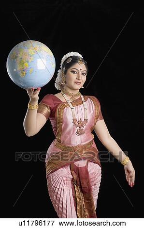 Stock Photo - Portrait of a young woman performing Bharatnatyam and holding a globe. Fotosearch