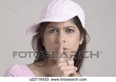Portrait of a young woman putting her finger on her lips View Large Photo Image Stock Image - Portrait of a young woman putting her finger on her lips. Fotosearch