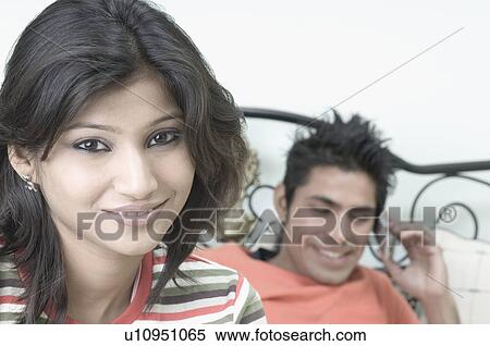 Portrait of a young woman smiling with a young man lying on the bed and talking on a mobile phone View Large Photo Image Stock Photography - Portrait of a young woman smiling with a young man lying on the bed and talking on a mobile phone . Fotosearch