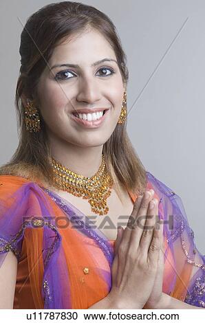 Portrait of a young woman standing with her hands folded View Large Photo Image Stock Image - Portrait of a young woman standing with her hands folded. Fotosearch