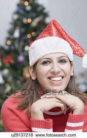 Portrait of a young woman wearing a Santa hat and smiling View Large Photo Image Stock Photo - Portrait of a young woman wearing a Santa hat and smiling. Fotosearch