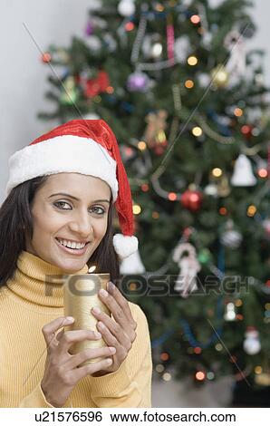 Stock Photograph - Portrait of a young woman wearing a Santa hat and holding a candle. Fotosearch